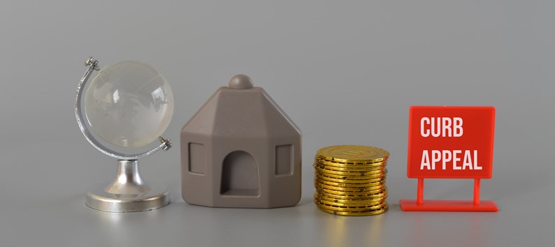 House model, coins, earth globe written with CURB APPEAL.Curb appeal refers to the visual attractiveness of a property, particularly its exterior or front-facing facade, as viewed from the street or sidewalk
