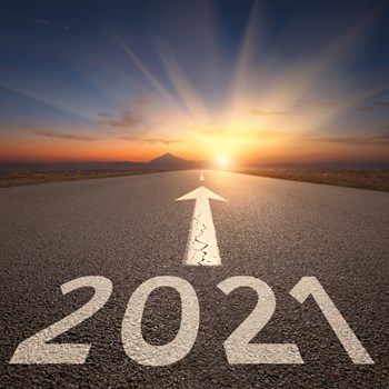 Driving on idyllic open road against the setting sun forward to upcoming 2021 new year. Concept for success and future.