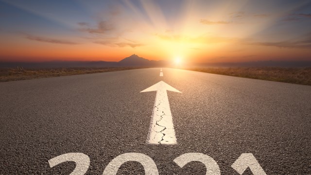 Driving on idyllic open road against the setting sun forward to upcoming 2021 new year. Concept for success and future.