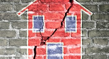 Cracked brick wall with a red house drawn on it -concept image