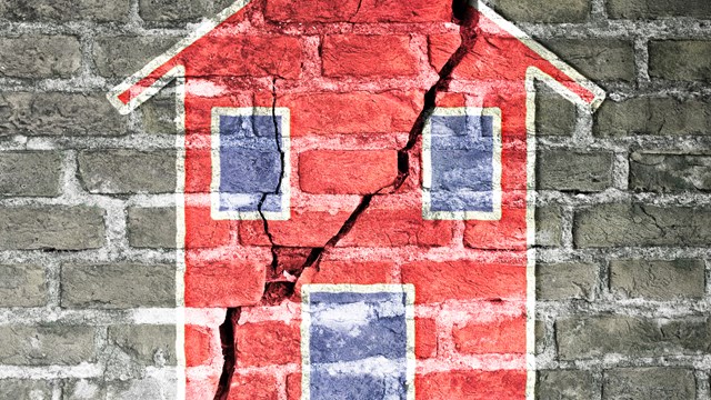 Cracked brick wall with a red house drawn on it -concept image