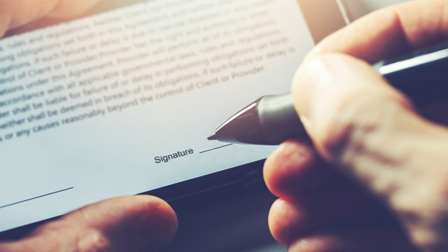 electronic signature concept - man sign distance contract with digital pen in mobile phone