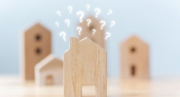 Real estate developer and managing property investment concept. Selective focus wooden houses with question mark on table