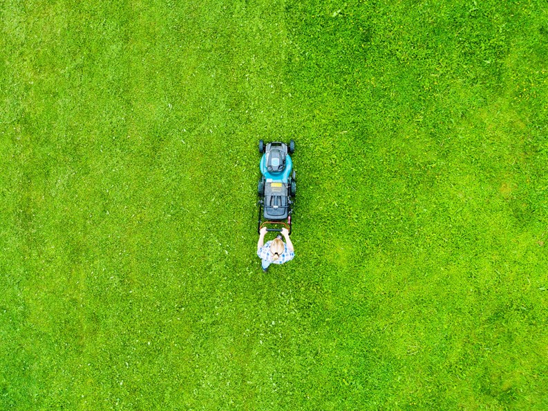 Beautiful girl cuts the lawn. Mowing lawns. Aerial view beautiful woman lawn mower on green grass. Mower grass equipment. Mowing gardener care work tool. Close up view. Aerial lawn mowing