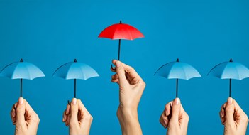 Loss, Insurance, & Claims Hand with miniature red umbrella isolated on blue background protect concept. Close up of different women hands holding little tiny blue umbrellas against while a red one differentiate itself. Investment protection and insurance concept, differentiate yourself from the crowd.