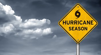 Yellow caution sign with black hurricane symbol, stormy sky in background 