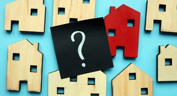 Tiny wooden houses and question mark. Home valuation and selection.