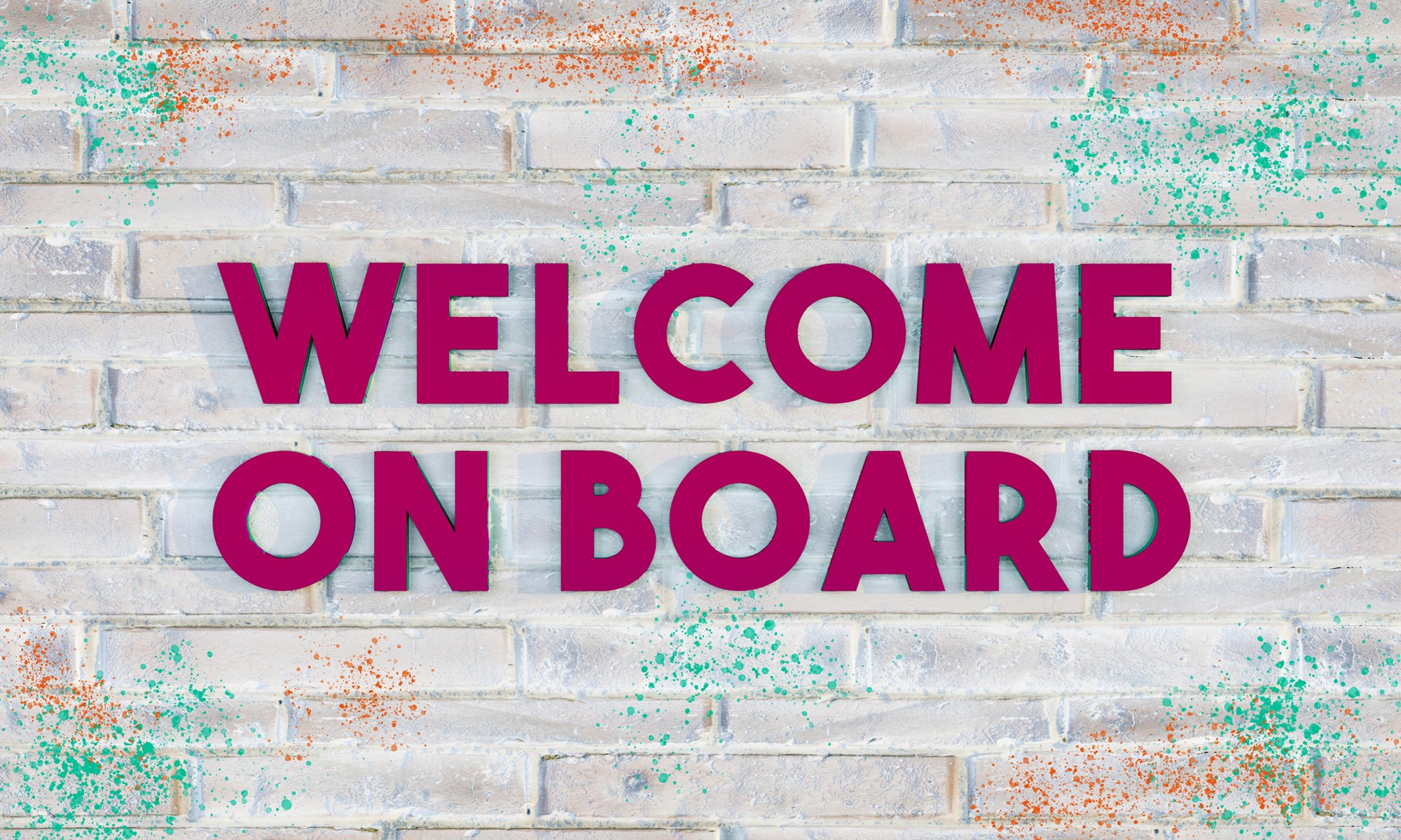 3D letters reading WELCOME ON BOARD in dark purple on a bright brick wall, with some colored paint-splatter.