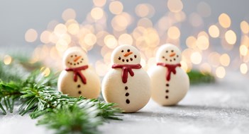 Multifamily Holiday Celebrations Variety of sweet macaroons. Fir branches on a gray background. Merry Christmas card. New year mood.