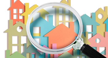 Real estate agent looks at the houses through a magnifying glass - Searching new home concept with colorful houses