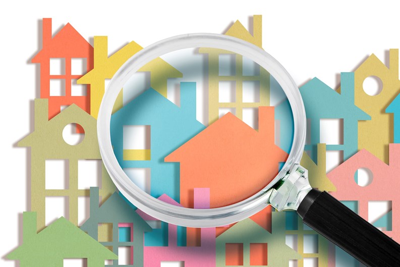 Real estate agent looks at the houses through a magnifying glass - Searching new home concept with colorful houses