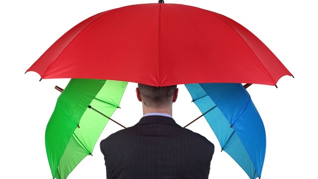 Confident businessman with three umbrellas concept for more than adequate ample insurance cover or failsafe backup plan