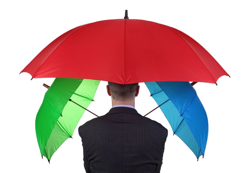 Confident businessman with three umbrellas concept for more than adequate ample insurance cover or failsafe backup plan