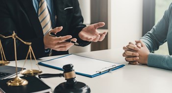 Litigation in Your Community Image lawyer businessman sitting at the office with a woman customer explaining the agreement of advice.