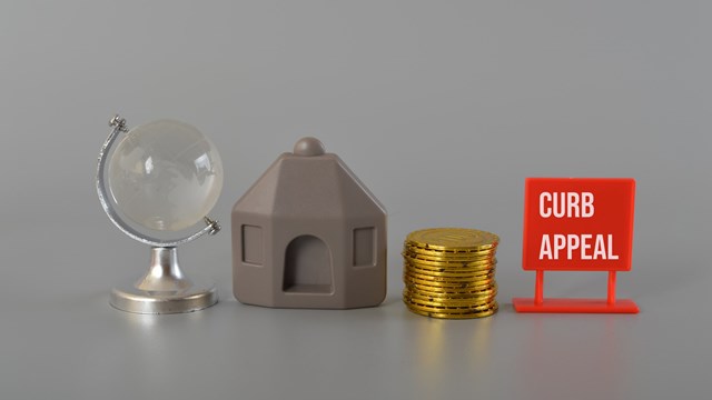 House model, coins, earth globe written with CURB APPEAL.Curb appeal refers to the visual attractiveness of a property, particularly its exterior or front-facing facade, as viewed from the street or sidewalk