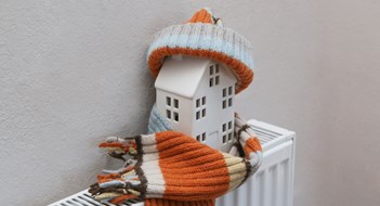 Essential Pre-Winter Maintenance for Buildings & HOAs Figure of house and warm clothes on heating radiator. Home heating expenses and savings concept.
