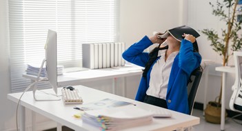 Avoiding Board Burnout Stressed businesswoman is covering her face with a notebook while sitting at her desk in a modern office, overwhelmed by work and seeking a moment of peace