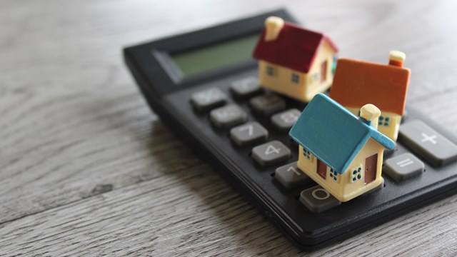 Toy house and calculator with copy space. Property, home insurance, buy, sell and rent concept.