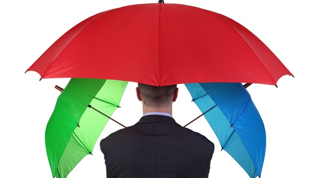 Confident businessman with three umbrellas concept for more than adequate ample insurance cover or failsafe backup plan