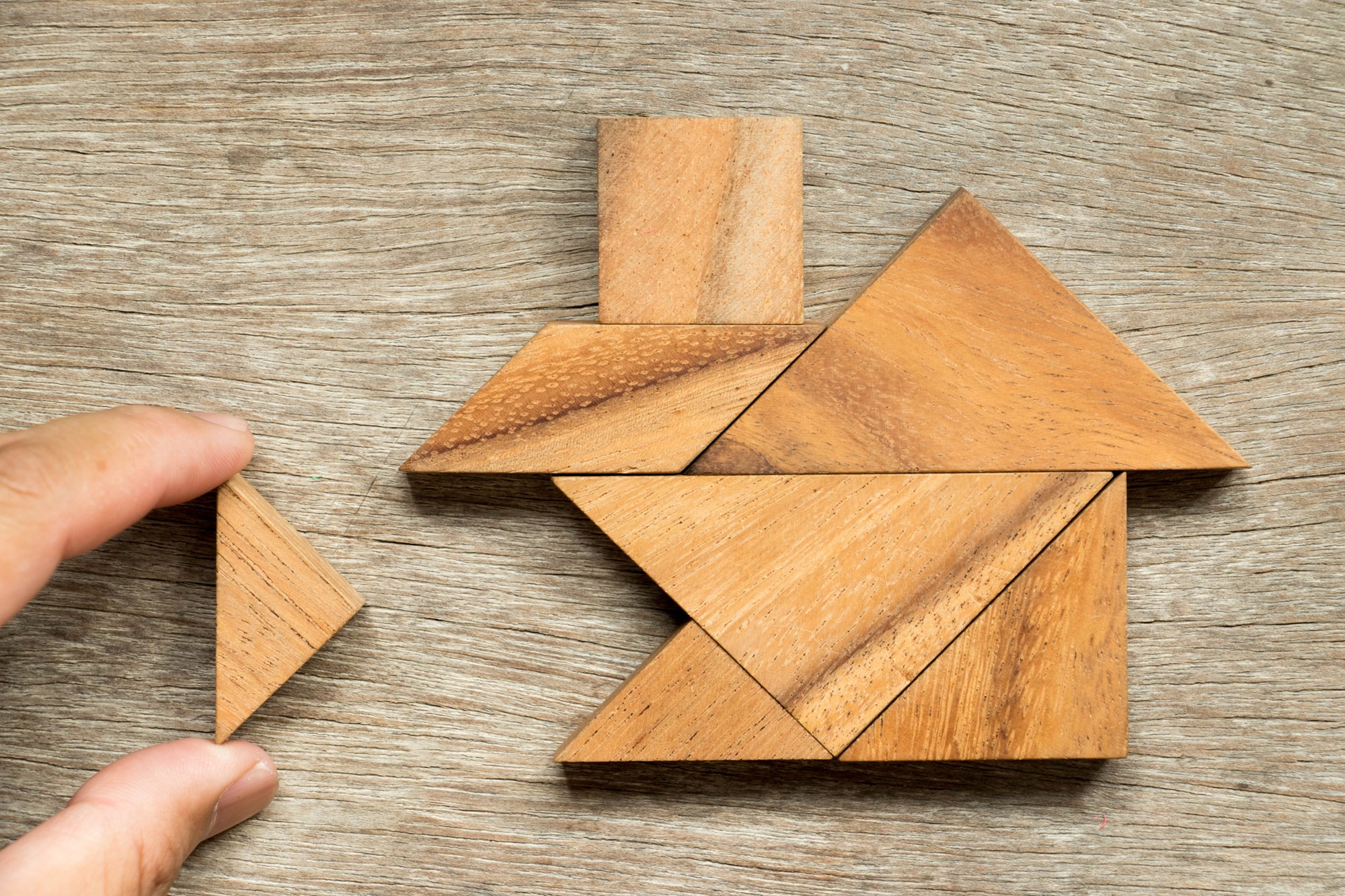 Wooden tangram puzzle in home shape wait for completion (Concept for family building or dream life)