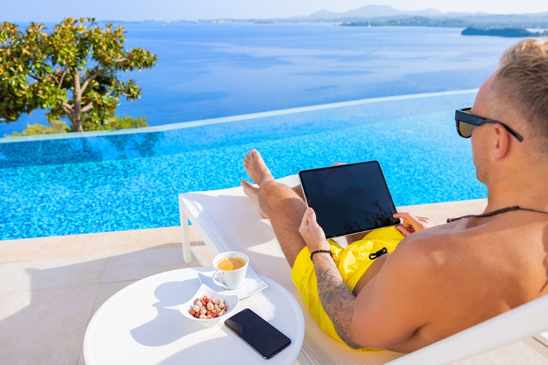 Man using digital tablet by infinity pool