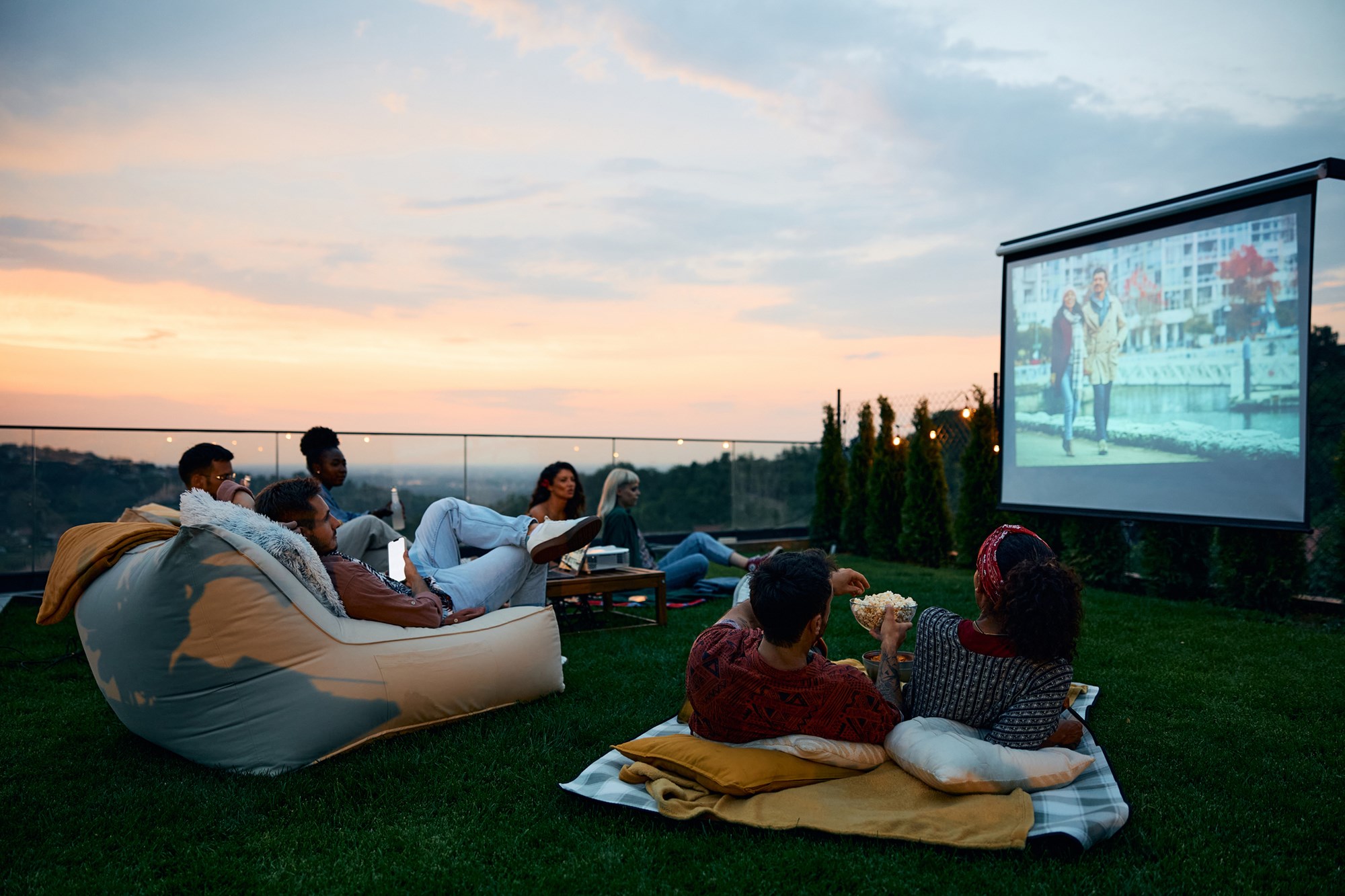 Multiracial friends enjoying in movie night in the backyard at sunset. Copy space.